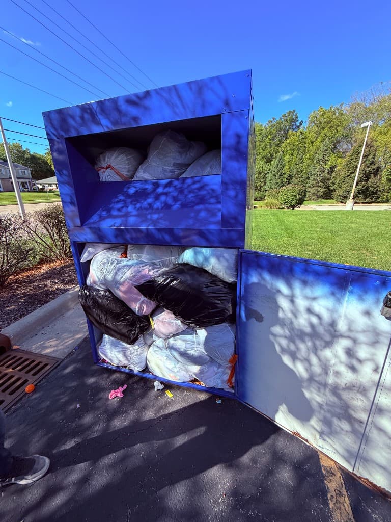 A driver's picture of an overflowing donation bin, bags stacked to the door